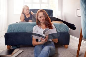 Two Female College Students In Shared House Bedroom Studying Together