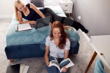Two Female College Students In Shared House Bedroom Studying Together