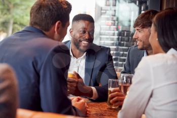 Group Of Business Colleagues Meeting For Drinks And Socializing In Bar After Work