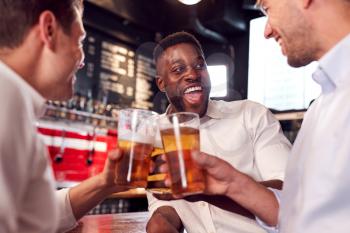 Three Men Making A Toast As They Meet For Drinks And Socialize In Bar After Work
