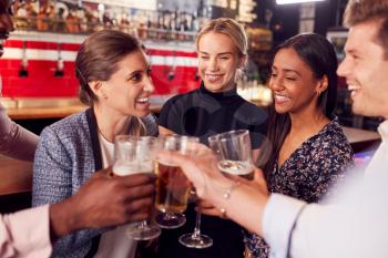 Male And Female Friends Making A Toast As They Meet For Drinks And Socializing In Bar After Work