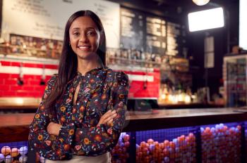 Portrait Of Smiling Female Bar Owner Standing By Counter
