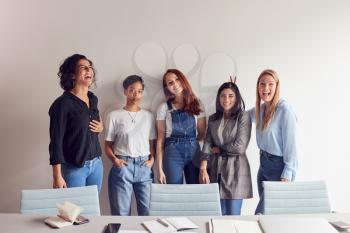 Portrait Of Young Female Business Team Standing By Table In Meeting Room In Modern Workspace