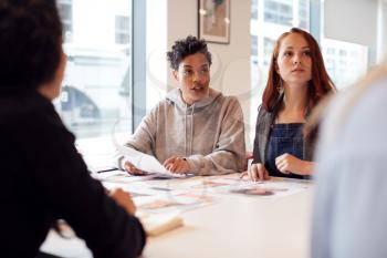 Team Of Young Businesswomen In Meeting Around Table In Modern Workspace