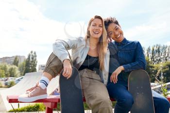 Portrait Of Two Female Friends With Skateboard In Urban Skate Park
