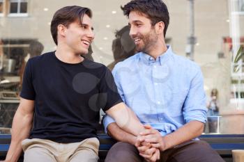 Loving Male Gay Couple Sitting Outside Coffee Shop Holding Hands