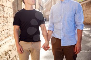 Close Up Of Male Gay Couple On Vacation Holding Hands Walking Along City Street
