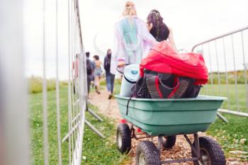 Close Up Of Trolley As Friends Arrive At Music Festival Carrying Camping Equipment Onto Site
