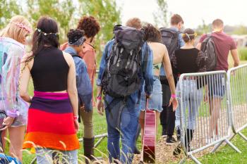 Rear View Of Friends At Entrance To Music Festival Walking Through Security Barriers