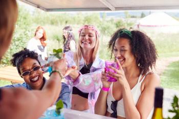 Female Friends Buying Drinks From Bar At Music Festival