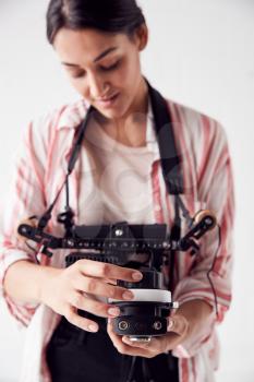 Female Crew Member On Video Film Set Operating Wireless Follow Focus Module In White Studio