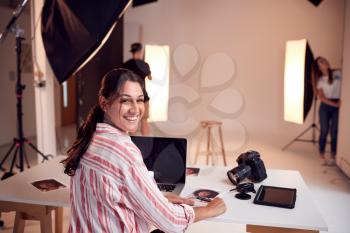 Portrait Of Professional Female Photographer Working In Studio With Assistants