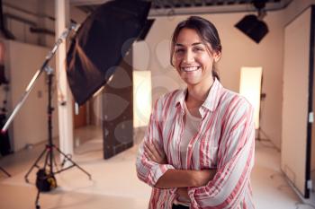 Portrait Of Smiling Female Photographer Standing In Studio With Lighting Equipment