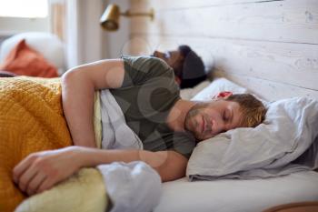 Loving Male Gay Couple Sleeping In Bed At Home Together
