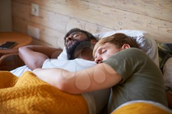 Loving Male Gay Couple Sleeping In Bed At Home Together