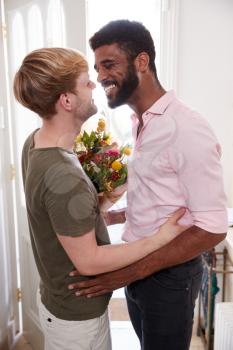 Man Opening Front Door To Gay Partner At Home Who Gives Him Bunch Of Flowers
