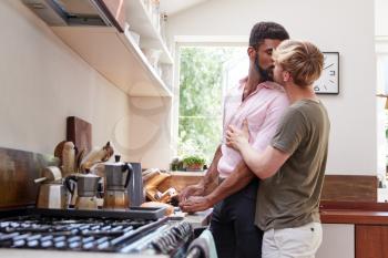 Loving Male Gay Couple At Home In Kitchen Making Breakfast Together