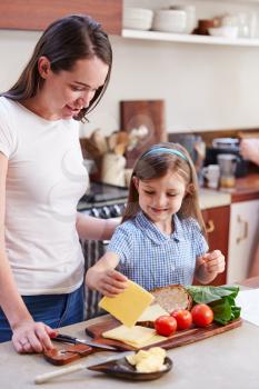 Same Sex Female Couple With Daughter Preparing School Lunchbox At Home Together