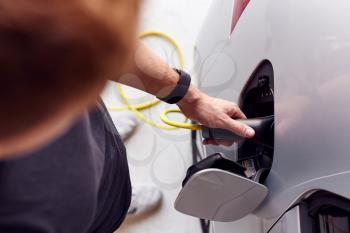 Close Up Of Hand Attaching Power Cable To Environmentally Friendly Zero Emission Electric Car
