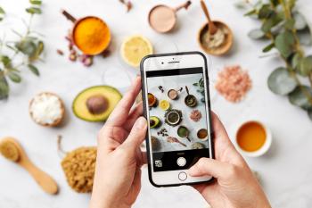 Woman Photographing Group Of Natural Beauty And Health Products On Marble Background With Mobile Phone
