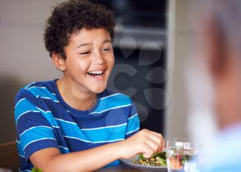 Close Up Of Boy As Multi-Generation Mixed Race Family Eat Meal Around Table At Home Together