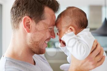 Close Up Of Loving Father Holding 3 Month Old Baby Daughter At Home