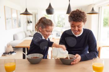 Children At Kitchen Counter Eating Sugary Breakfast Before Going To School