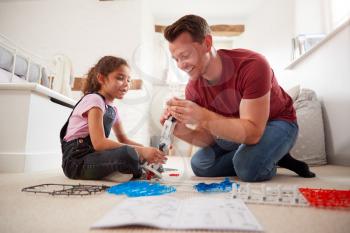 Father And Daughter In Bedroom Building Robot Kit Together