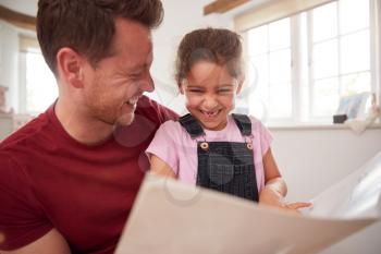 Father And Daughter In Bedroom Reading Book Together
