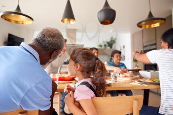 Multi-Generation Mixed Race Family Eating Meal Around Table At Home Together