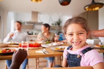 Portrait Of Granddaughter As Multi-Generation Mixed Race Family Eat Meal Around Table At Home