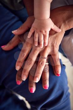 Close Up Of Mother With Daughter And Baby Granddaughter From Multi-Generation Family Holding Hands
