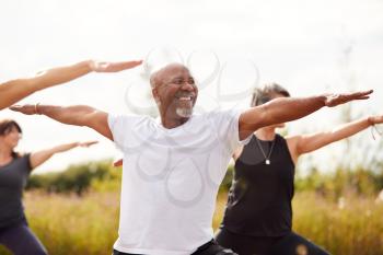 Group Of Mature Men And Women In Class At Outdoor Yoga Retreat