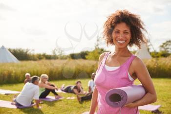 Portrait Of Mature Woman On Outdoor Yoga Retreat With Friends And Campsite In Background