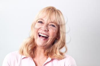 Studio Shot Of Laughing Mature Woman Against White Background At Camera
