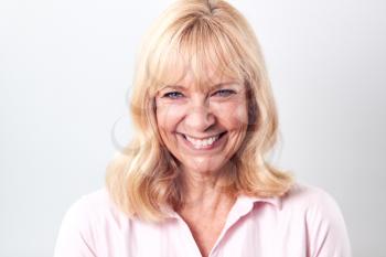 Studio Shot Of Smiling Mature Woman Against White Background At Camera