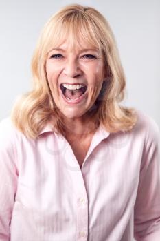 Studio Shot Of Laughing Mature Woman Against White Background At Camera