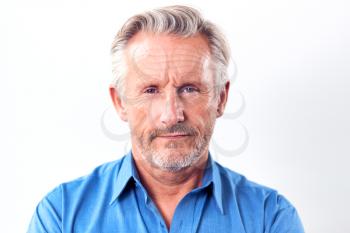 Studio Shot Of Mature Man With Serious Expression Against White Background At Camera