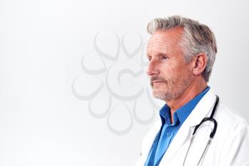 Profile Studio Shot Of Mature Male Doctor Wearing White Coat And Stethoscope On White Background