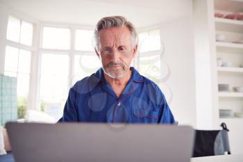 Mature Man In Wheelchair Looking Up Information About Medication Online Using Laptop