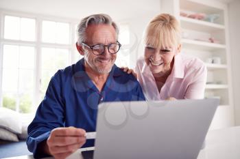 Mature Couple At Home Looking Up Information About Medication Online Using Laptop
