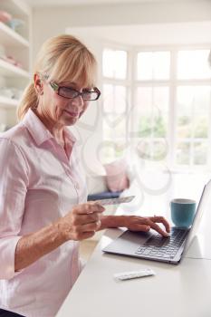 Mature Woman At Home Looking Up Information About Medication Online Using Laptop