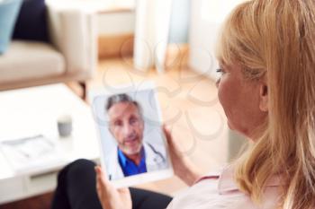 Mature Woman Having Online Consultation With Doctor At Home On Digital Tablet