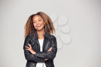 Waist Up Studio Shot Of Happy Young Woman With Folded Arms Wearing Leather Jacket Smiling At Camera