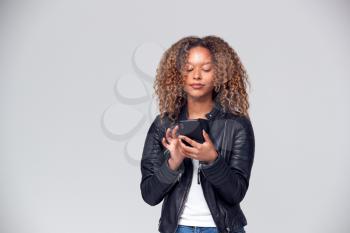 Studio Shot Of Woman Wearing Leather Jacket Using Mobile Phone