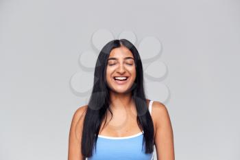 Studio Portrait Of Positive Happy Young Woman With Eyes Closed Smiling At Camera
