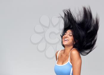 Studio Portrait Of Positive Happy Young Woman Flicking Long Hair