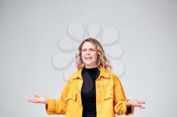 Studio Shot Of Angry Woman Shouting Off Camera Against White Background