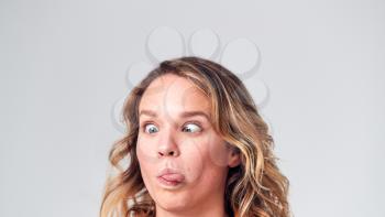 Head And Shoulders Studio Shot Of Woman Pulling Faces And Smiling At Camera