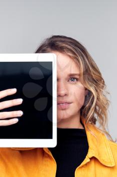 Studio Portrait Of Smiling Young Woman Covering Face With Digital Tablet